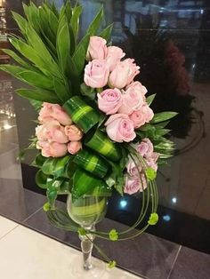 a vase filled with pink roses and greenery on top of a marble countertop