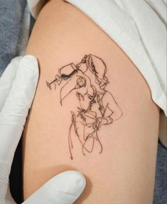 a woman's thigh with a tattoo design on the back of her leg, and a gloved hand holding it