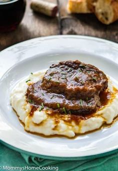 a white plate topped with mashed potatoes covered in gravy and meatloaf