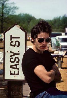 a man wearing sunglasses leaning against a sign