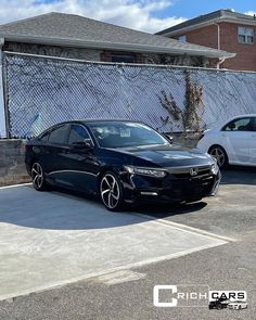 two cars parked next to each other in front of a fenced area with a chain link fence