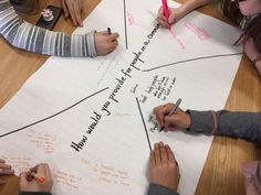 several people sitting around a table writing on paper