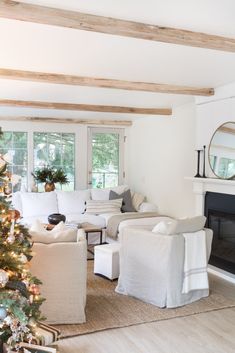 a living room filled with furniture and a christmas tree in front of a fire place