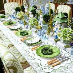 the table is set with green plates and place settings