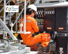 a man in an orange jumpsuit is working on a machine at a power station