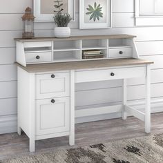 a white desk with drawers and two pictures on the wall