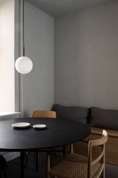 a black table with two plates on it in front of a window and bench next to it