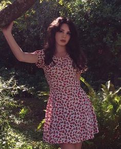 a woman in a red and white dress posing for the camera with her arms behind her head