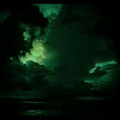 the sky is filled with dark clouds and green light