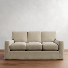 a beige couch sitting on top of a wooden floor