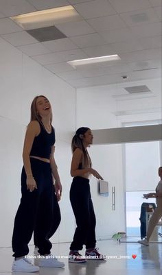 two women are dancing in an empty room