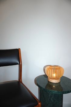 a chair next to a table with a lamp on it and a black leather chair