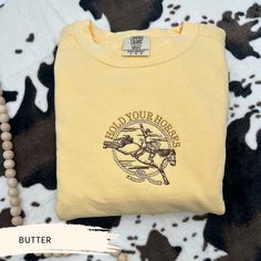 🐎🌾 Embroidered Hold Your Horses Sweatshirt - Western Charm with a Playful Twist! Embrace the spirit of the Wild West with our Hold Your Horses Sweatshirt. This Western Crewneck is perfect for cowboys and cowgirls who love a blend of traditional style and modern wit. Whether you're headed to a rodeo, out on the ranch, or just love the cowboy aesthetic, this sweatshirt adds a fun, embroidered twist to your outfit. The comfortable fit and unique design make it ideal for casual days or a night out Western Crewneck, Hold Your Horses, Sweatshirt Western, Western Sweatshirts, Horse Sweatshirts, Cowboy Chic, Cowboy Aesthetic, The Cowboy, The Wild West