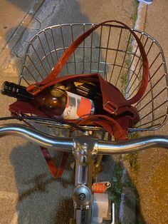 a wine bottle in a basket on the handlebars of a bicycle with other items