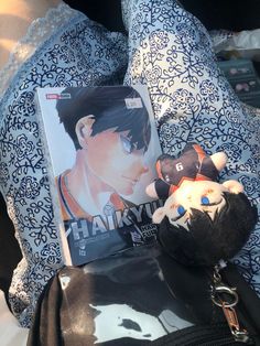 a stuffed animal is sitting next to a book on a bed with blue and white pillows