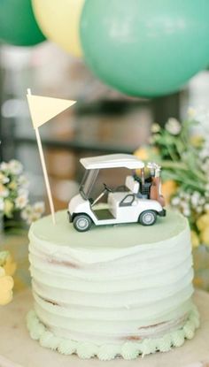 a wedding cake with a golf car on top and balloons in the background at a reception