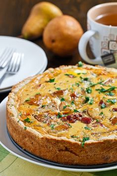 an omelet on a plate with silverware and pears in the background