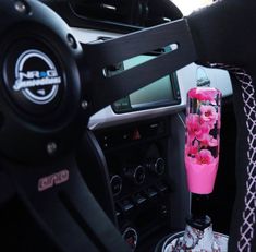 a pink vase sitting on top of a car dashboard next to a steering wheel control