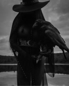 black and white photograph of a woman with a crow on her arm, wearing a hat