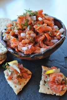 a bowl filled with food next to crackers on top of a blue table cloth