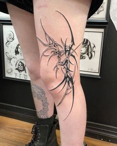 a woman's legs with tattoos on them and black boots in front of her