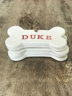 a white dog bone with the word duke painted on it