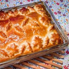 a casserole dish with meat and cheese in it on a floral tablecloth