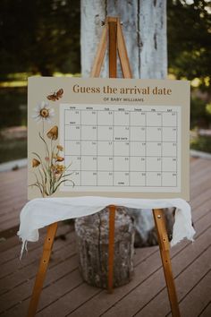 an easel with a calendar on it sitting in front of a wooden tree trunk