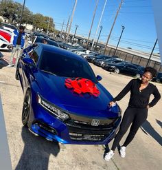 a woman standing next to a blue car with red bows on it's hood