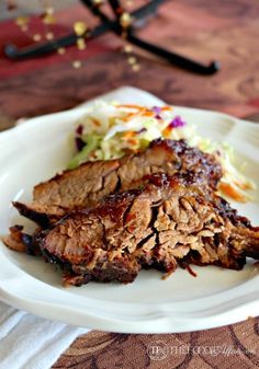 two pieces of meat on a plate with coleslaw