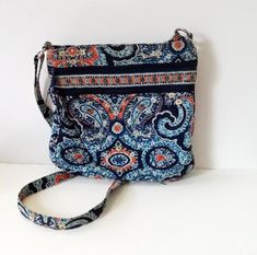 This quilted fabric shoulder or crossbody bag was made for Vera Bradley. It features a blue and orange paisley design. The top has a zip closure. Approximately 11" x 11", it has an adjustable shoulder strap, 2 zippered slip pockets on the front, and a zippered pocket on the inside. The shoulder strap is adjustable and the inside is lined with a contrasting blue fabric. It is in great condition! Wonderful piece for collectors! Free shipping in the USA  Want to see more purses: https://www.etsy.co Quilted Fabric, Blue And Orange, Paisley Design, Blue Fabric, Cross Body Handbags, Vera Bradley, Purses And Handbags, Jewelry Shop, Paisley