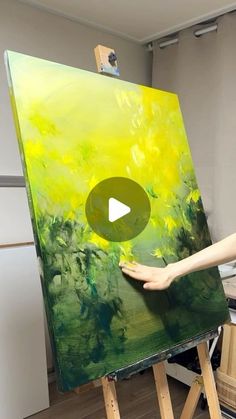 a woman is painting on an easel with yellow flowers and green leaves in the background