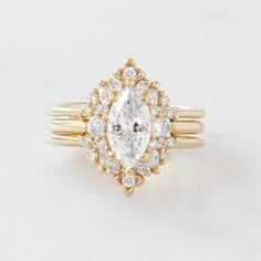 a yellow gold ring with an oval cut diamond surrounded by smaller round diamonds on each band