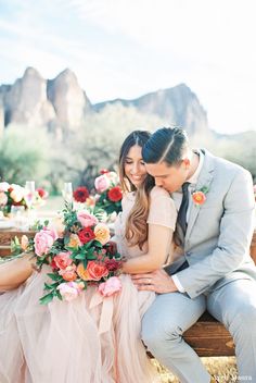 a man and woman sitting on a bench with flowers