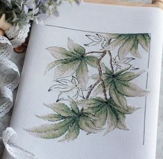 a cross - stitch pattern with flowers and lace on the table next to some scissors