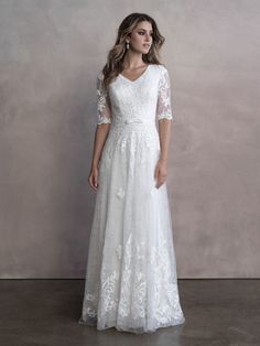 a woman in a white wedding dress standing against a wall