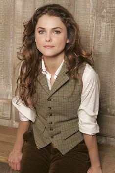 a woman sitting on top of a wooden bench wearing a suit and tie with long hair