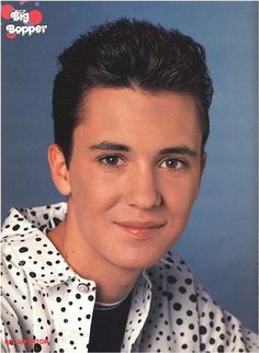 a close up of a person wearing a polka dot shirt and smiling at the camera