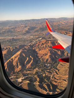 the view out an airplane window shows mountains and valleys