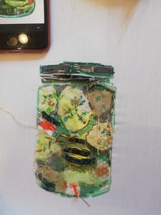 there is a cell phone on the table next to a jar with buttons in it