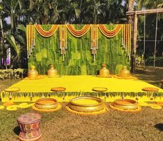 an outdoor stage set up with yellow and green decorations on the grass, surrounded by palm trees