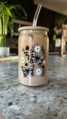 a glass jar sitting on top of a counter with butterflies painted on the inside of it