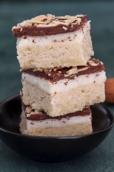 three pieces of cake sitting on top of a black plate next to a cinnamon stick