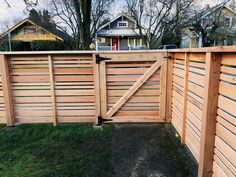 a wooden fence with an open gate on the top and bottom part, in front of a house