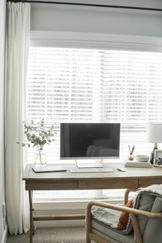 a desk with a computer on it in front of a window