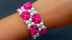 a pink and white beaded bracelet on someone's arm with pearls in the middle