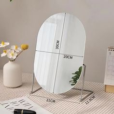 a round mirror sitting on top of a table next to a vase with flowers in it