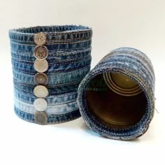 two stacks of blue jeans with coins on them and one rolled up in the shape of a tube