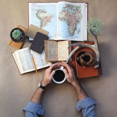 a man sitting at a table with an open book and coffee cup