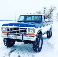 a blue and white truck parked in the snow